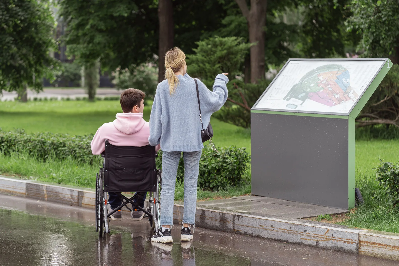 A young couple examines a park map, with one partner in a wheelchair, on a rainy day. Accessible Weekend Destinations Ideas Across the U.S.