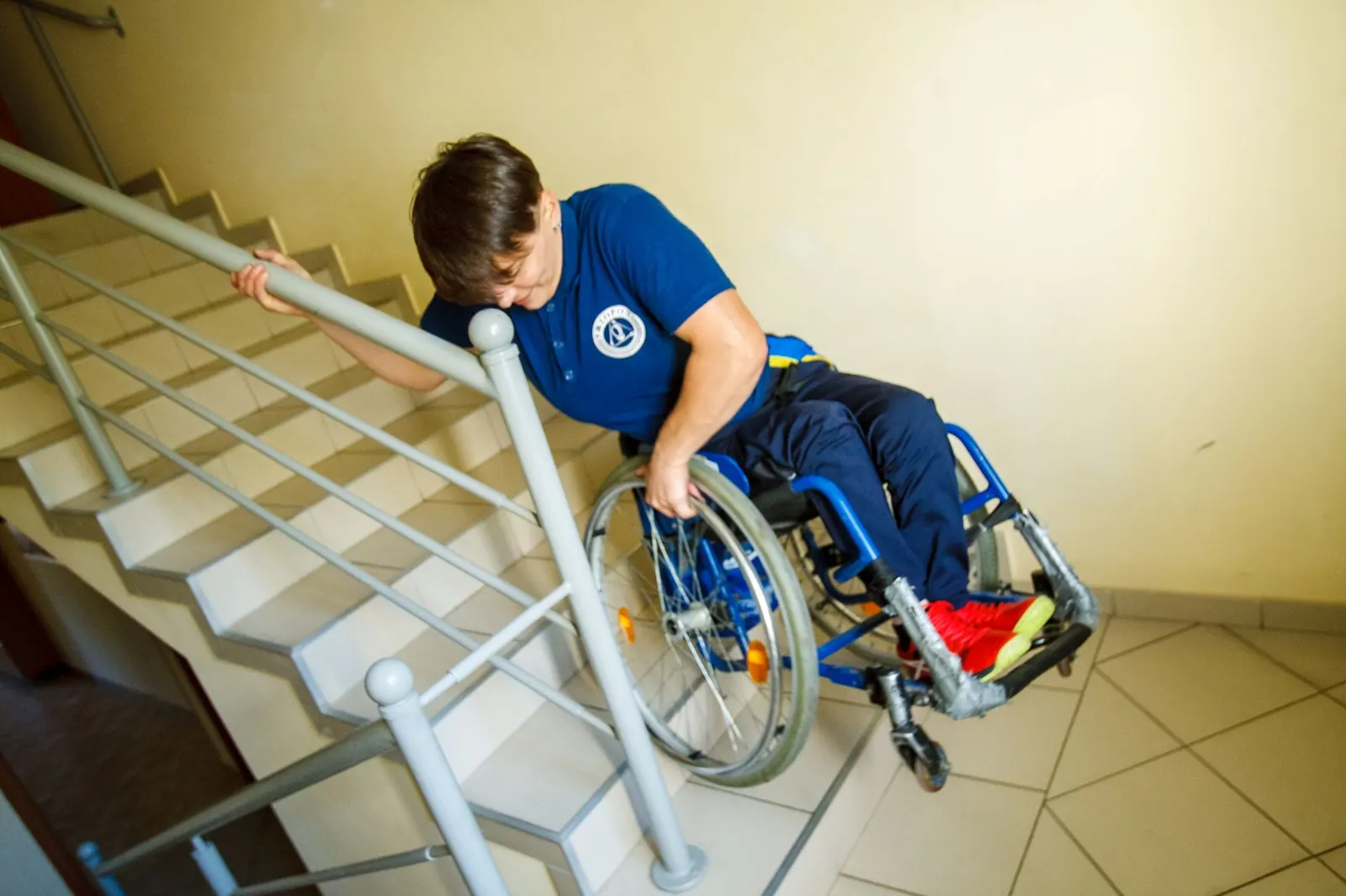 A person in a wheelchair navigating stairs with a handrail indoors, representing accessibility challenges. Photographing an accessible tour: what belongs in the frame, and what does not