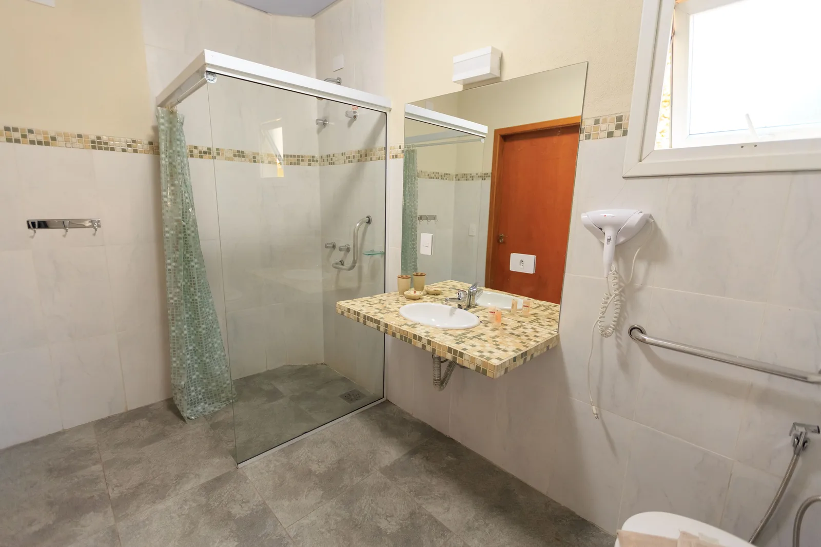 Spacious and accessible bathroom featuring a large glass shower, modern sink, and stylish decor. Photographing mobility-friendly hotels: bathroom first, then the exits