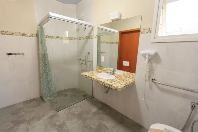 Spacious and accessible bathroom featuring a large glass shower, modern sink, and stylish decor. Photographing mobility-friendly hotels: bathroom first, then the exits