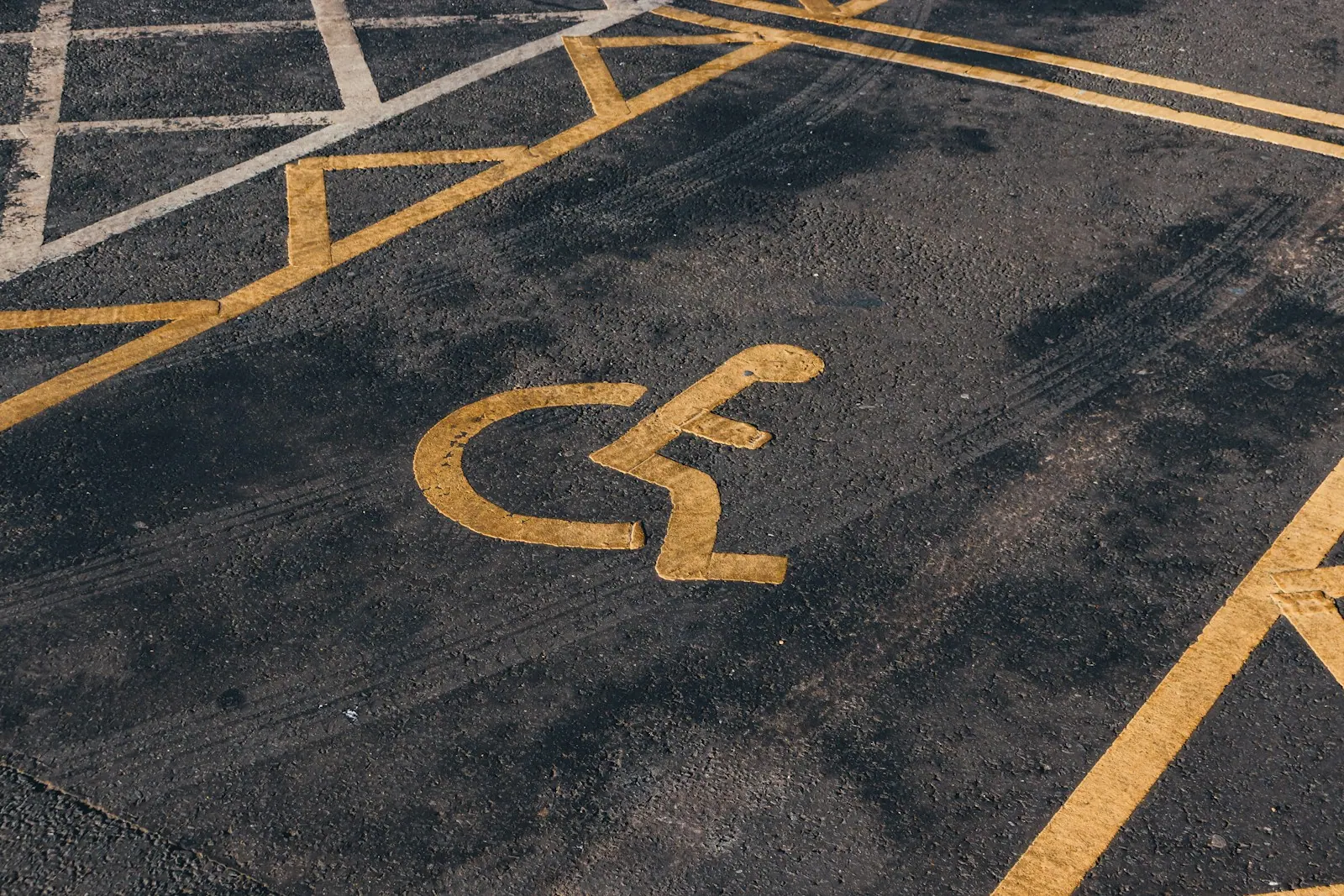a parking lot with a handicapped sign painted on it Disabled parking. Accessible parking spot. Blue badge. Yellow wheelchair sign on the ground