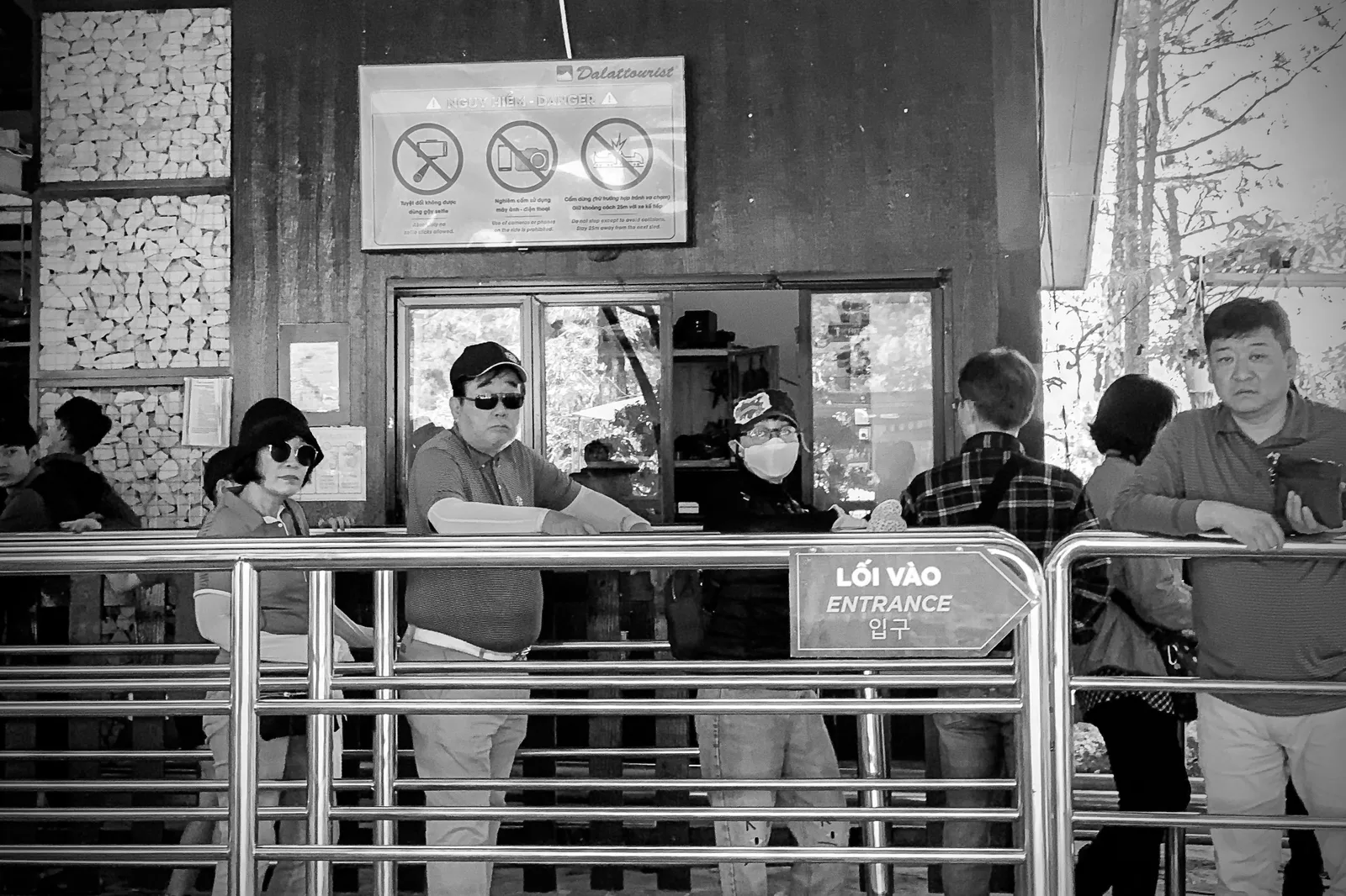 People waiting in line at an entrance with safety signage, captured in monochrome. A packing list for an accessible attraction visit