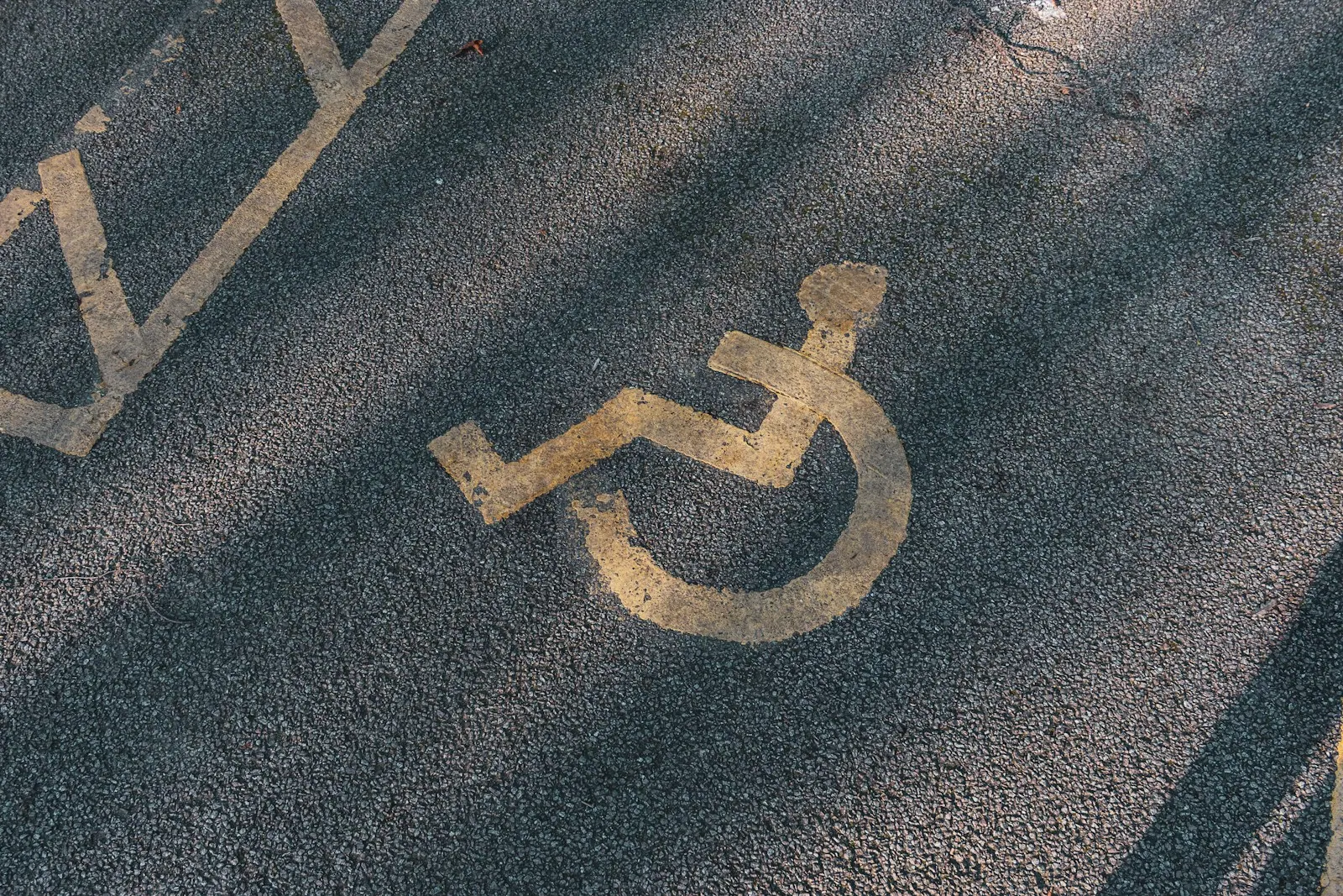 a handicapped sign painted on the asphalt of a street Disabled parking. Accessible parking spot. Blue badge. Yellow wheelchair sign on the ground. Accessible travel mistakes: first visit tips