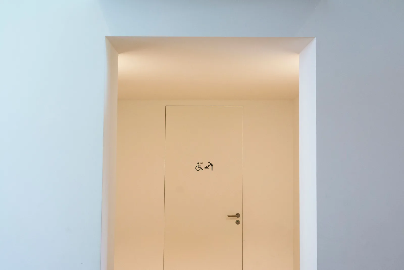 A clean and minimalist indoor space featuring an accessible restroom sign on a closed door. Realistic pricing for accessible travel: what local businesses can change
