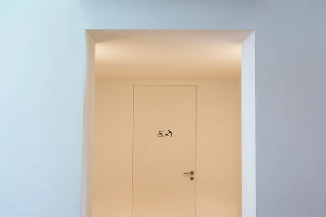 A clean and minimalist indoor space featuring an accessible restroom sign on a closed door. Realistic pricing for accessible travel: what local businesses can change