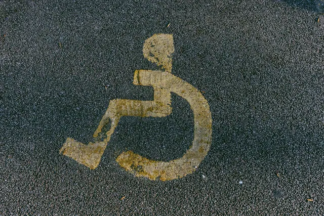 a handicapped sign is painted on the pavement Disabled parking. Accessible parking spot. Blue badge. Yellow wheelchair sign on the ground. How to avoid accessible travel mistakes in 2027
