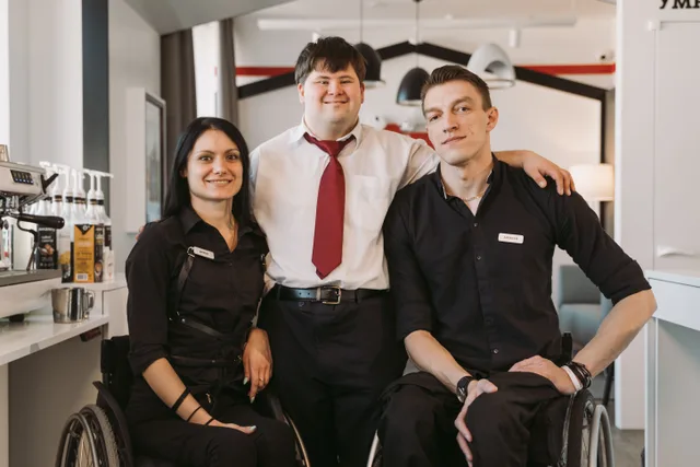 A group of diverse adults, including those in wheelchairs, smiling in a cafe environment fostering teamwork. Accessible travel mistakes travelers can avoid