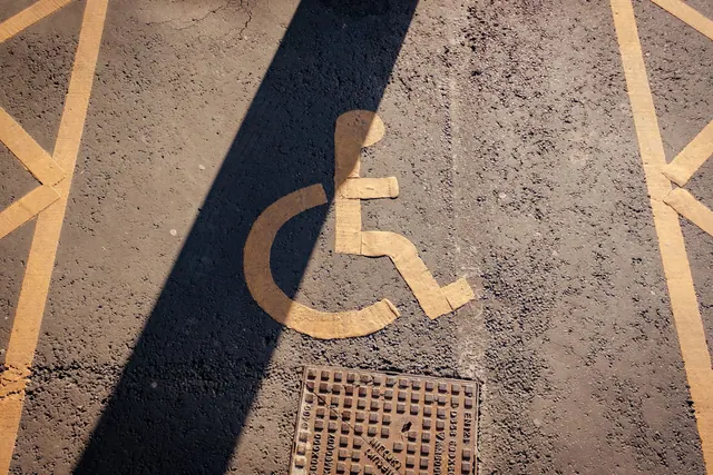 Close-up of a yellow wheelchair symbol painted on asphalt, highlighting accessibility.