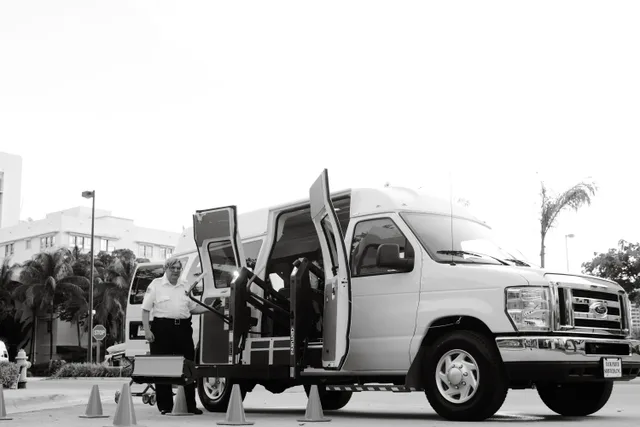 A black and white image depicting an accessible transport van with a lift, enhancing mobility for passengers with disabilities. Wheelchair accessible trips cost: what to budget for