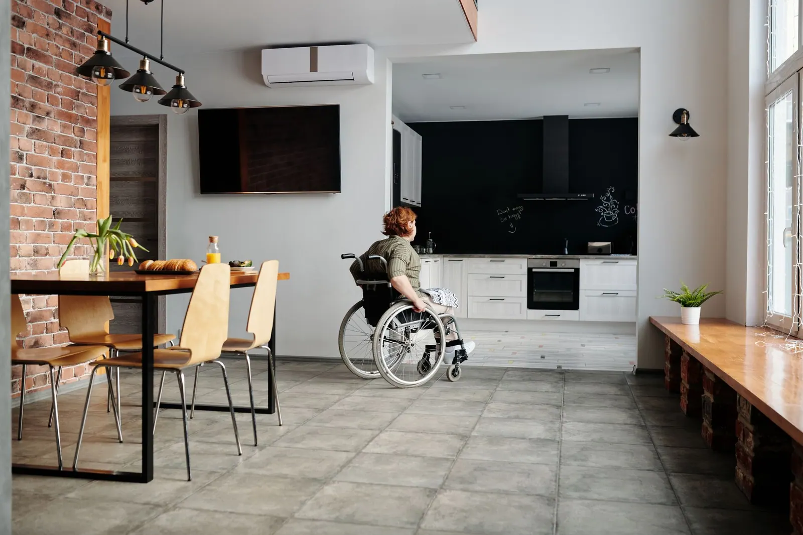 A woman in a wheelchair in a modern kitchen and dining space, highlighting accessibility. Accessible travel lodging when a trip has gone wrong before